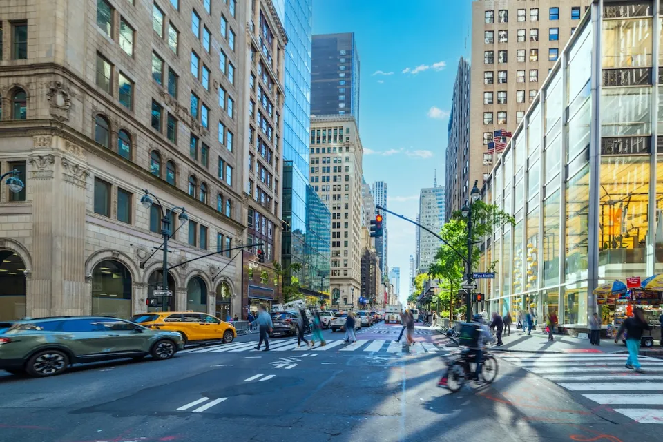 Crosswalk in New York City with cars, bikes, and pedestrians.